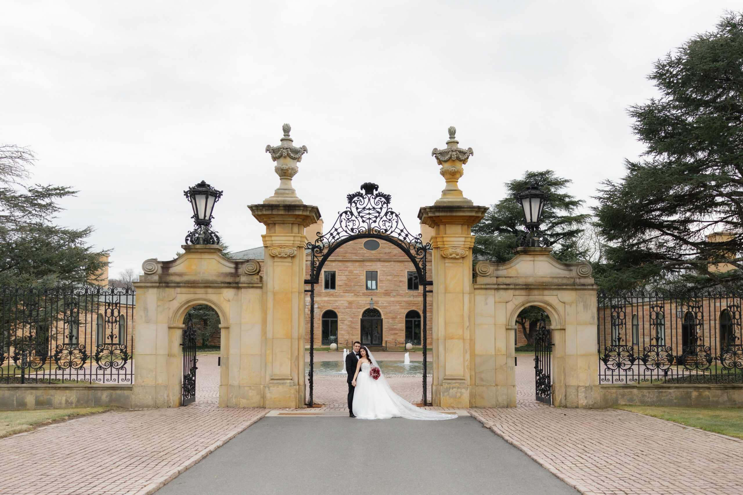 Bride and groom at a grand estate entrance of Jasna Polana wedding venue in New Jersey, showcasing elevated New Jersey wedding planning with coordinated timeline flow and venue logistics handled seamlessly.