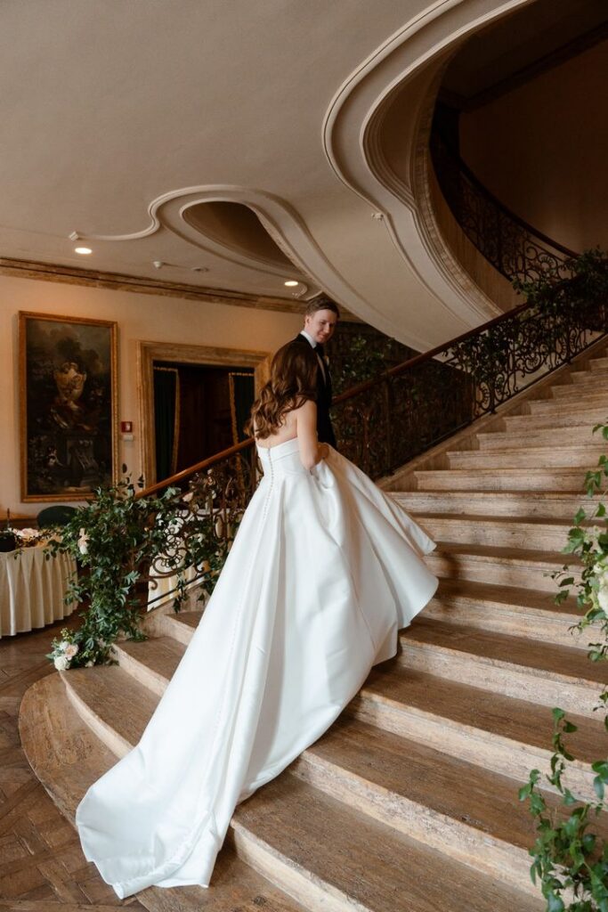 Bride making her way down the grand staircase for a first look at a luxury New Jersey wedding venue, highlighting thoughtful wedding planning and timeless design.