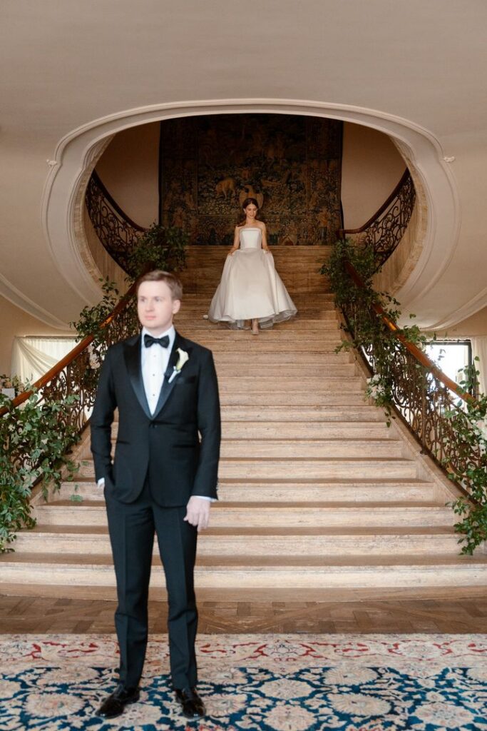 Bride and groom walking hand in hand down a grand staircase during their New Jersey wedding, representing confident wedding planning decisions and an organized wedding day.