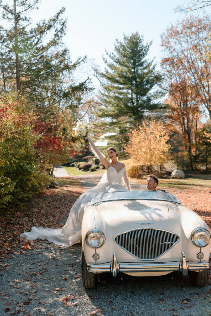 Bride posing on a vintage car during an outdoor fall wedding photoshoot