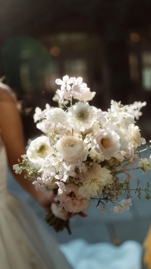Wedding bouquet with white and blush flowers held by the bride